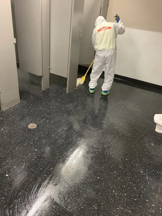 Technician in protective gear cleaning a contaminated black water floor in San Marino