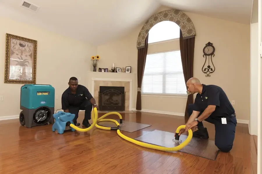 Technicians extracting water from a soaked hardwood floor in a San Marino home